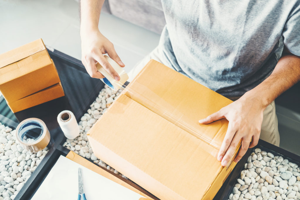 A man taping a cardboard box package.