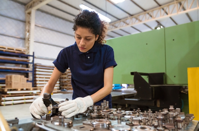 Manufacturing worker wearing gloves assembles a technical product.