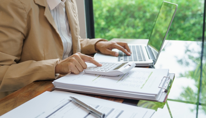 Employee reviewing ITAD budget data on a laptop in a corporate setting.
