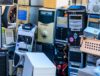 A pile of old computer towers and electronic devices stacked for e-waste recycling at a certified facility.